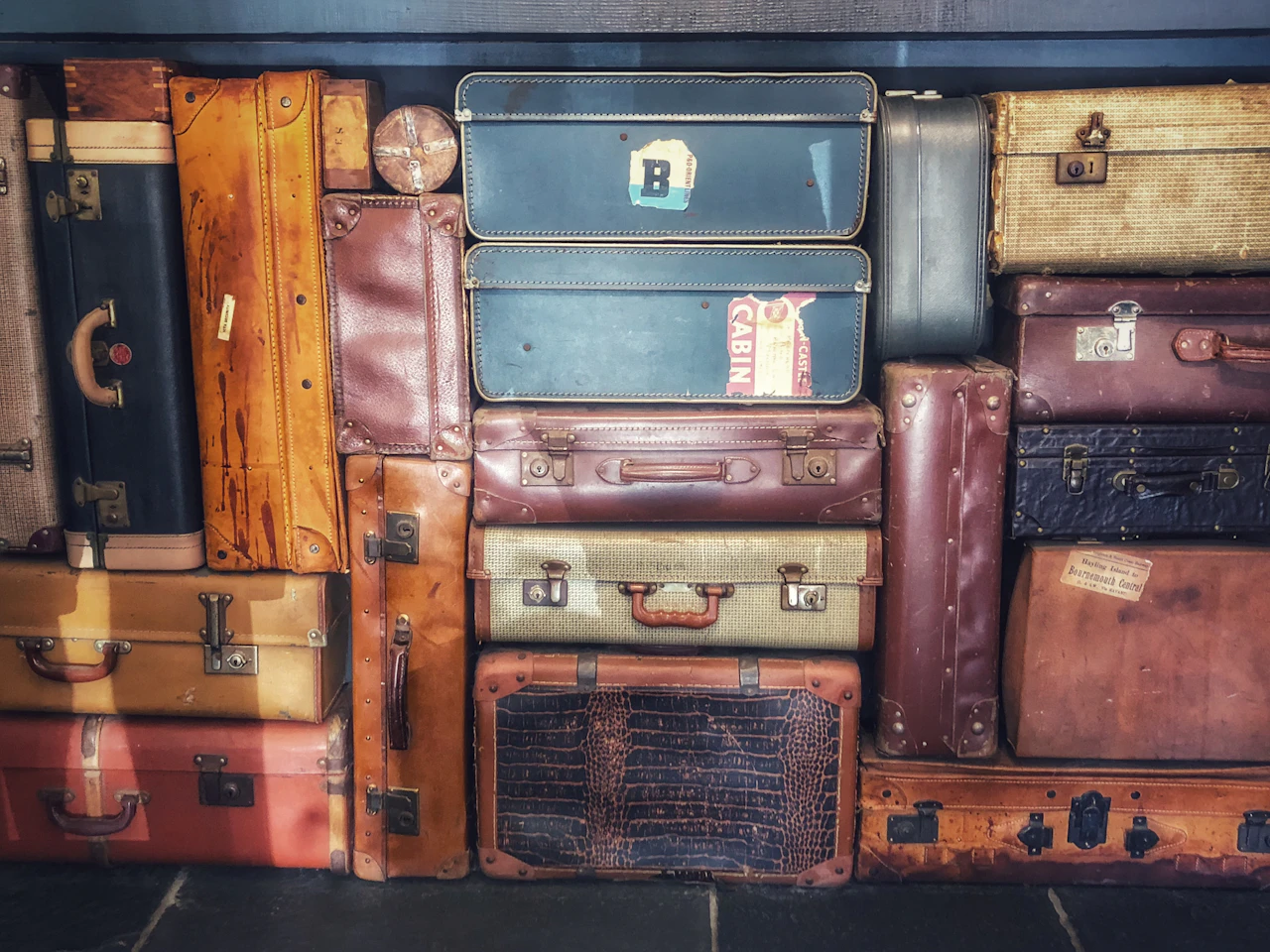 A display of stacked leather and fabric travel suitcases