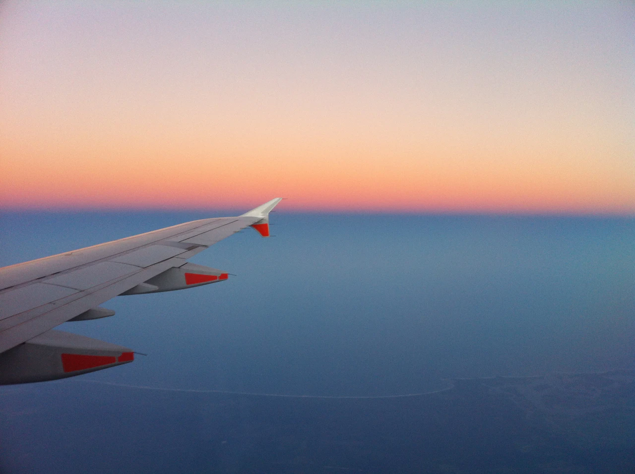 View from an aircraft window with a wing against the evening sky
