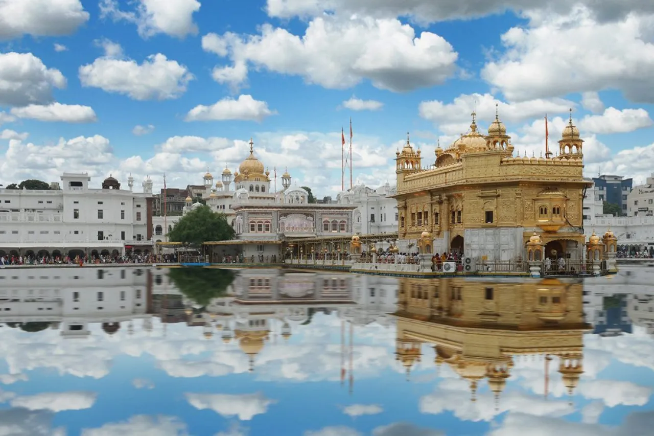 The Golden Temple in Amritsar and its reflection in the sarovar under a blue sky