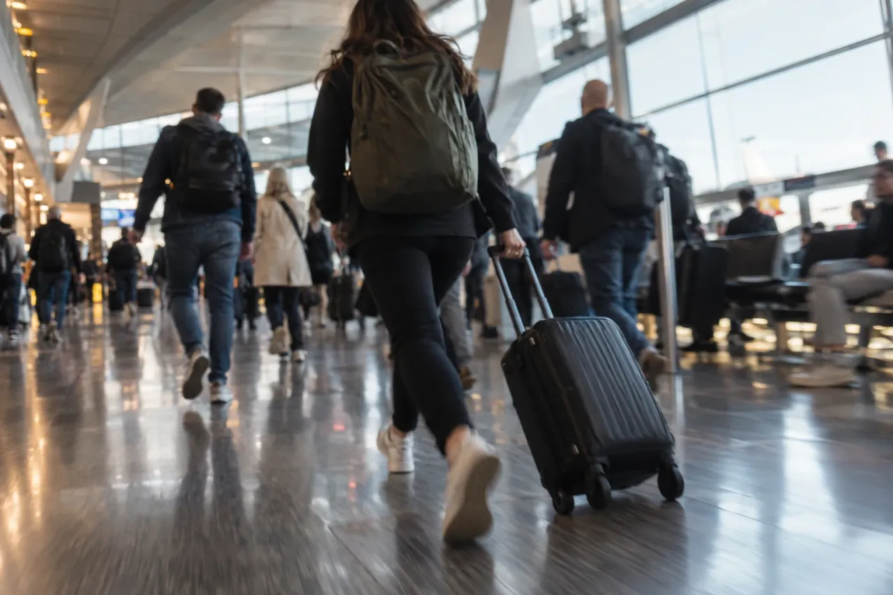 A traveller walking quickly through an airport terminal with a cabin bag
