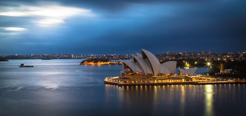 Sydney Opera House glowing beside the harbour at dusk